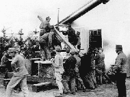 Установка 8-см полевой пушки М5/8 на импровизированный зенитный лафет. Среди солдат, которые снизу толкают ствол орудия, выделяется второй слева тем, что носит парадный мундир мирного времени